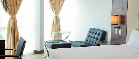 Una habitación de hotel moderna con una cama grande, un escritorio, una silla y una mesita.