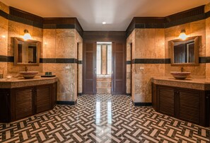 A hotel bathroom with two sinks, a mirror, and a patterned floor.