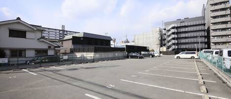 A parking lot with marked spaces, a building with a sign reading "TAIHO" on the right, and a clear sky.
