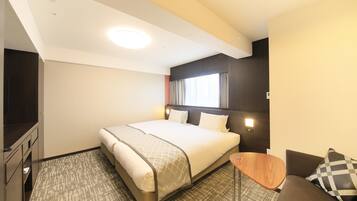 A hotel room with a bed, a small table, a sofa, and a TV.