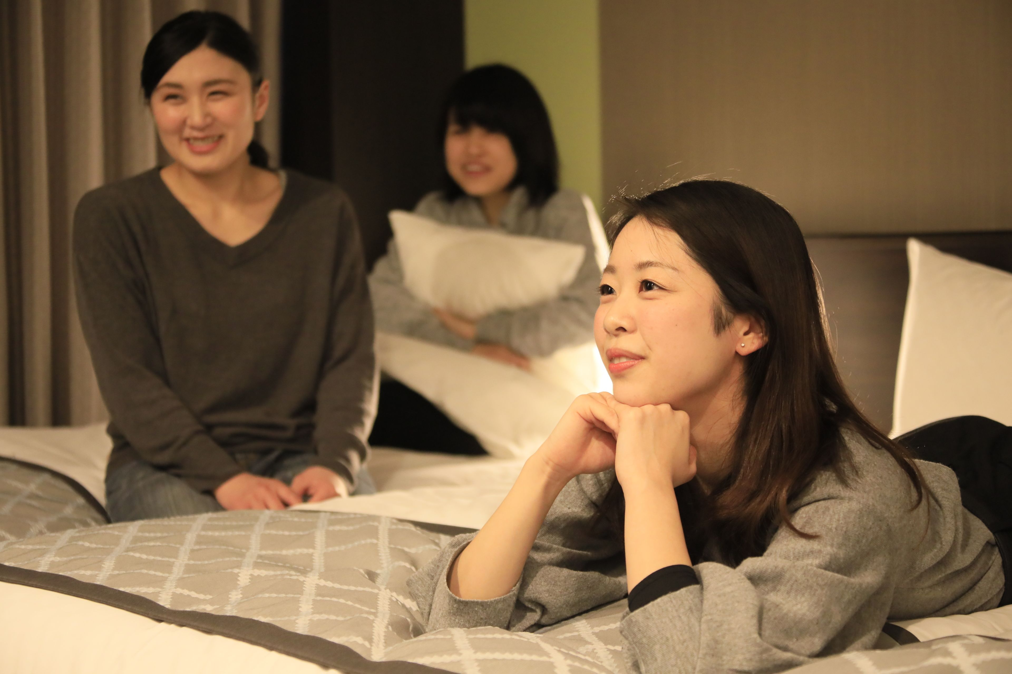 A room with a bed, pillows, and a person sitting on the bed.