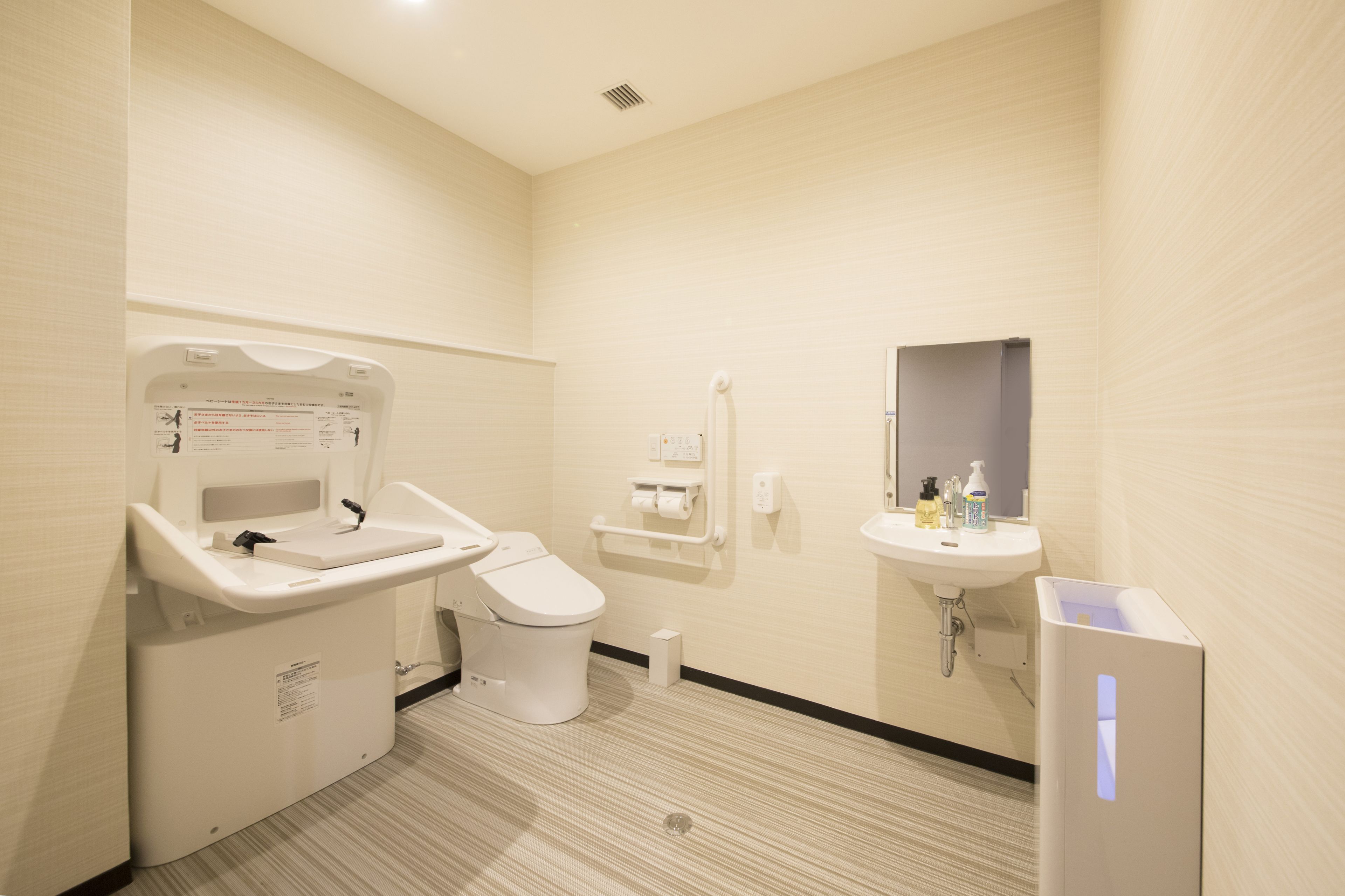 A modern bathroom with a toilet, sink, and hand dryer.