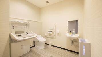 A modern bathroom with a toilet, sink, and hand dryer.