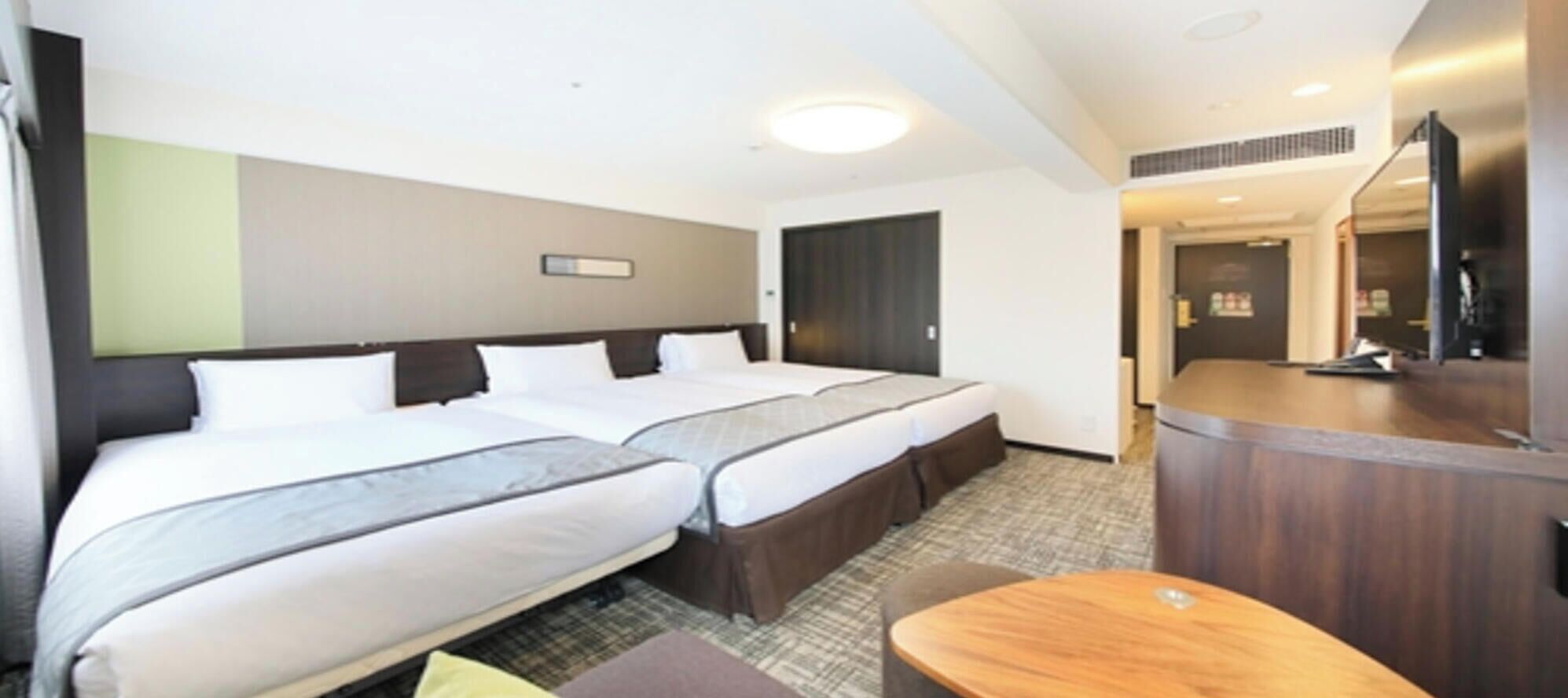 A hotel room with two beds, a small seating area, and a reception desk.