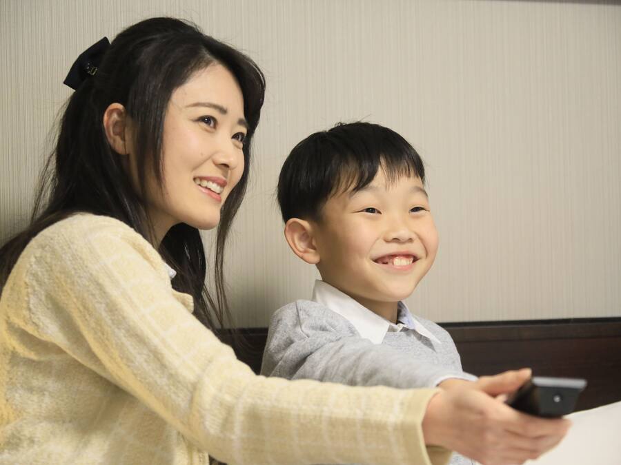 A woman and a child sitting at a table with a smartphone.