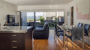A modern kitchen with a large island, dining area with chairs, and a view of the outdoors.