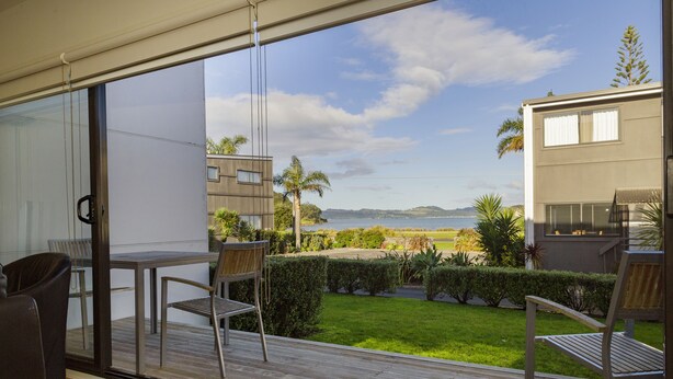 A balcony with a view of a landscaped garden and a body of water.