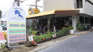 A hotel named 'Cozy Rabbit' with a signboard, outdoor seating area, and potted plants. - Cozy Rabbit Hotel (Thung Song)
