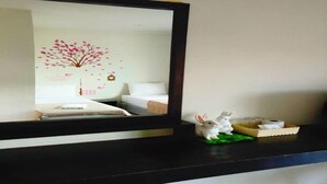 A hotel room with a bed, a dresser, a mirror, and a small white rabbit figurine on the dresser. - Cozy Rabbit Hotel (Thung Song)