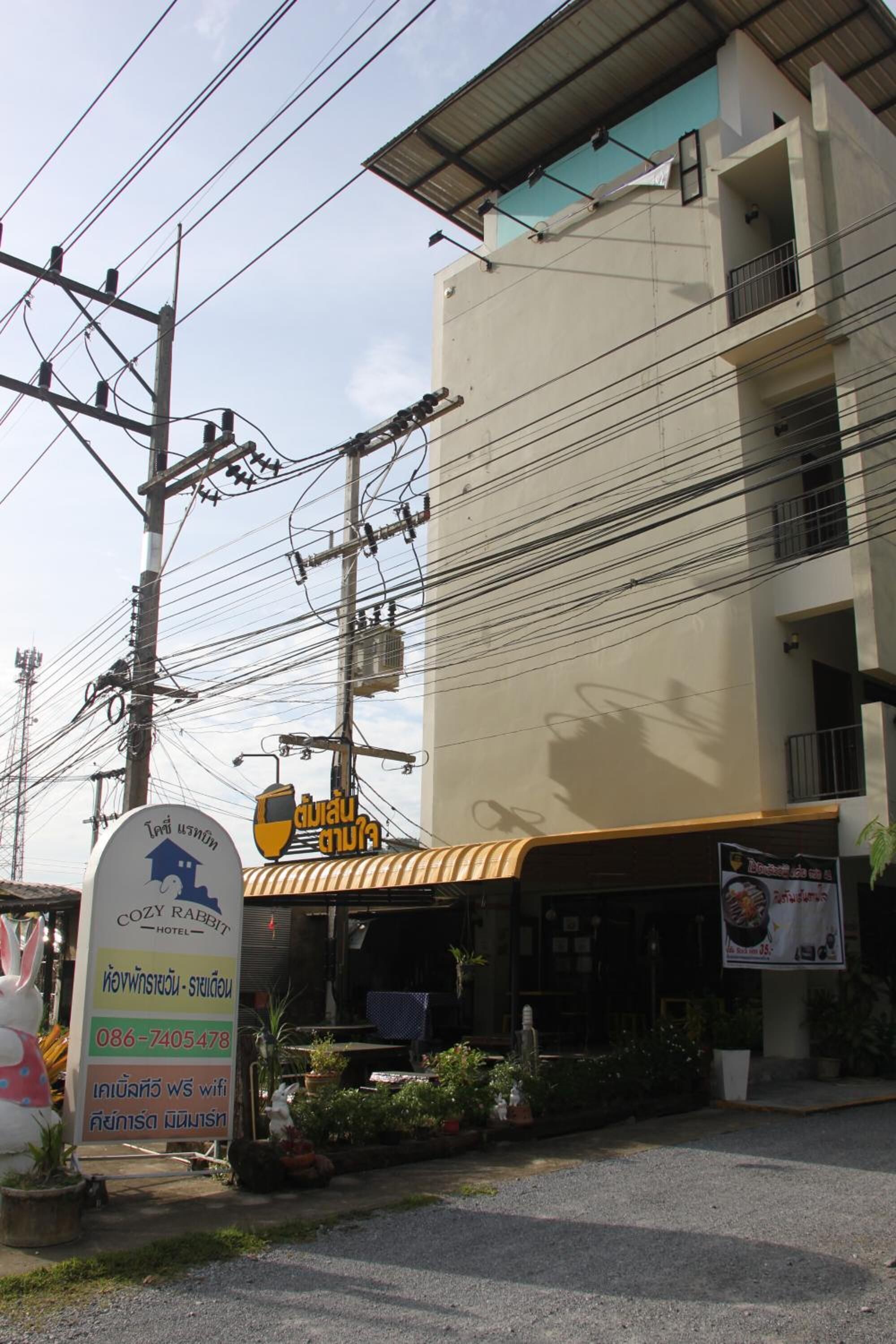 A hotel with a signboard advertising a 'COZY RABBIT HOTEL' and contact number.