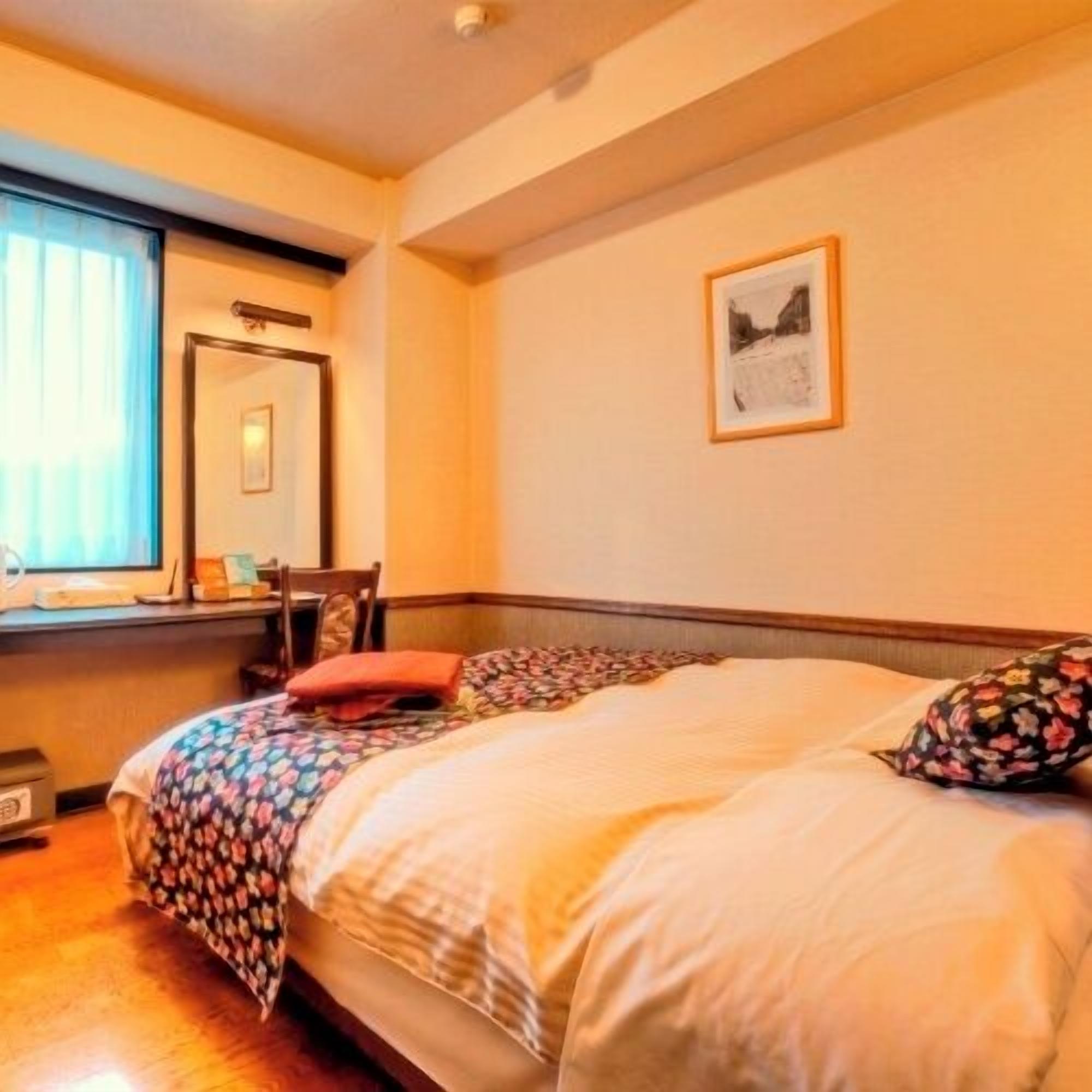 A bedroom with a bed, a window with curtains, a framed picture on the wall, and a wooden headboard.