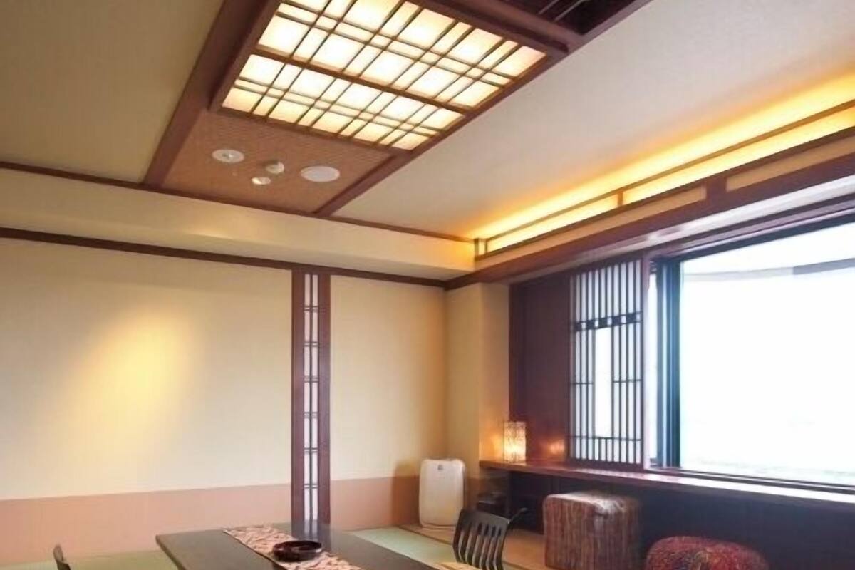 A traditional Japanese room with tatami flooring, a low table, cushions, and a sliding door.