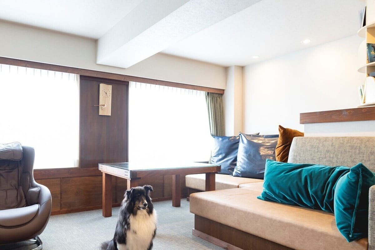 A modern living room with a sofa, a massage chair, a wooden table, and a dog.
