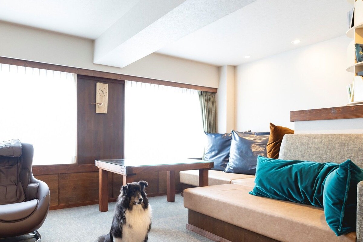 A modern living room with a sofa, a massage chair, a wooden table, and a dog.