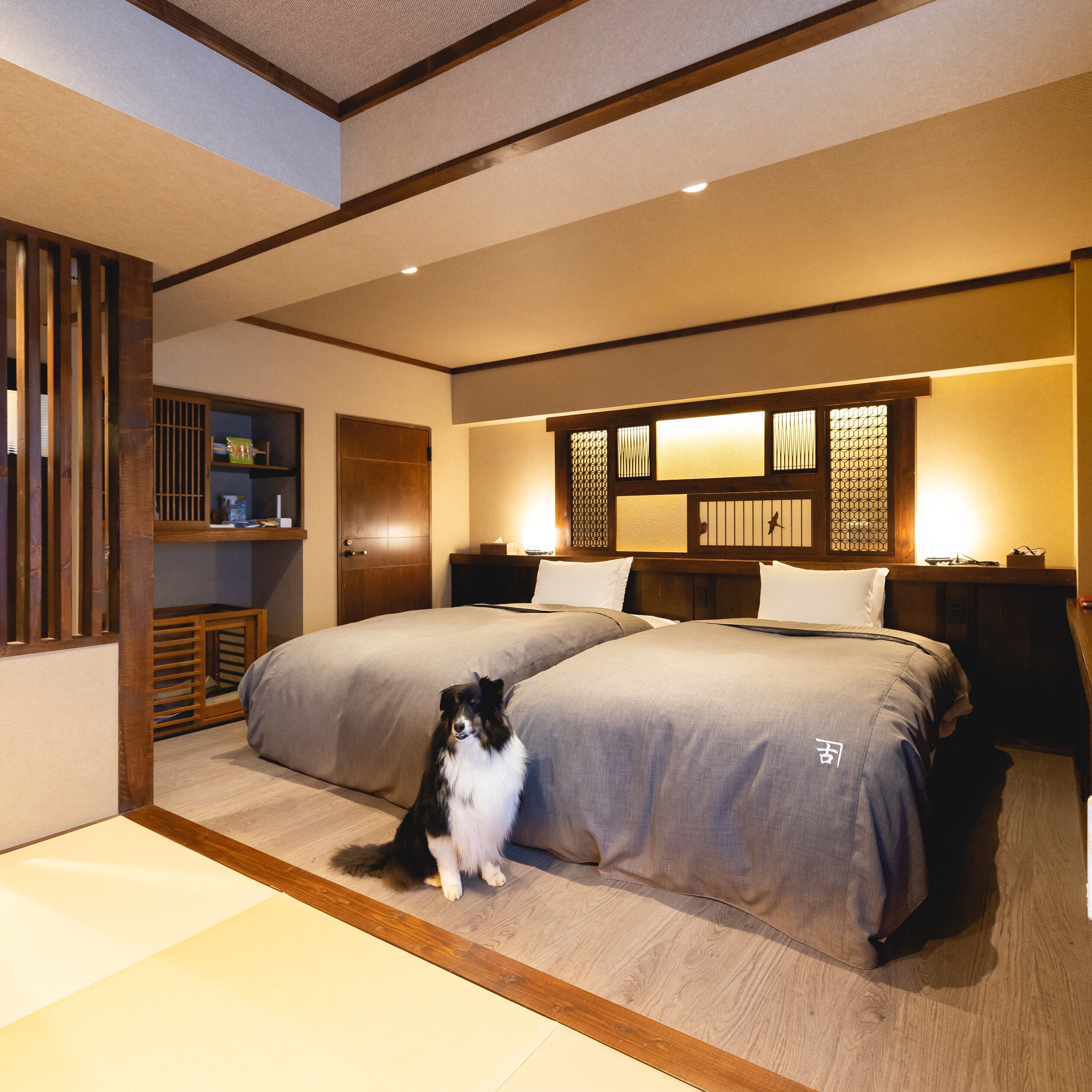 A bedroom with two beds, a wooden floor, a cat, and a traditional Japanese-style partition.
