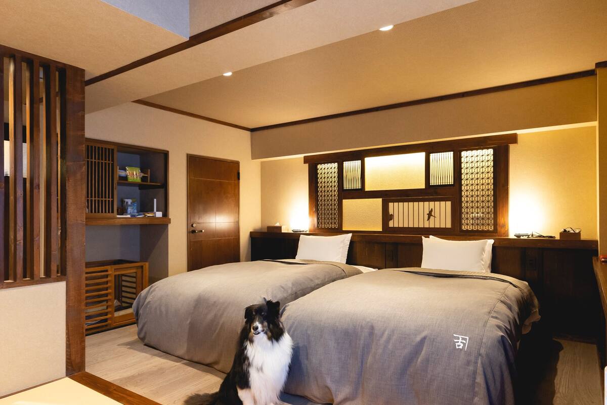 A bedroom with two beds, a wooden floor, a cat, and a traditional Japanese-style partition.