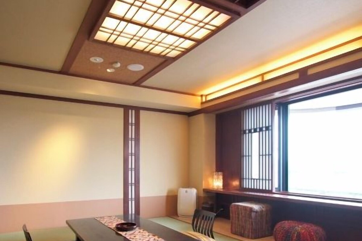 A traditional Japanese room with tatami flooring, a low table, cushions, and a sliding door.