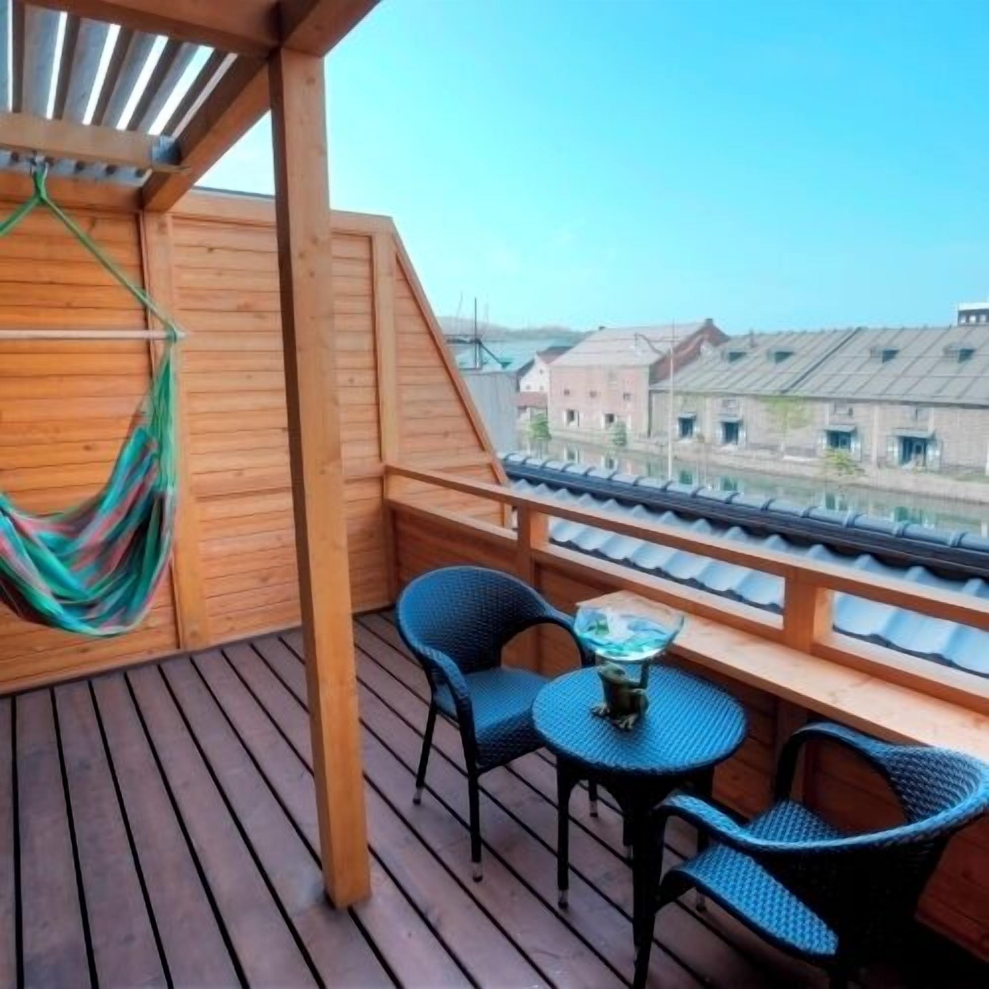A wooden deck with a hammock, two chairs, and a small table.