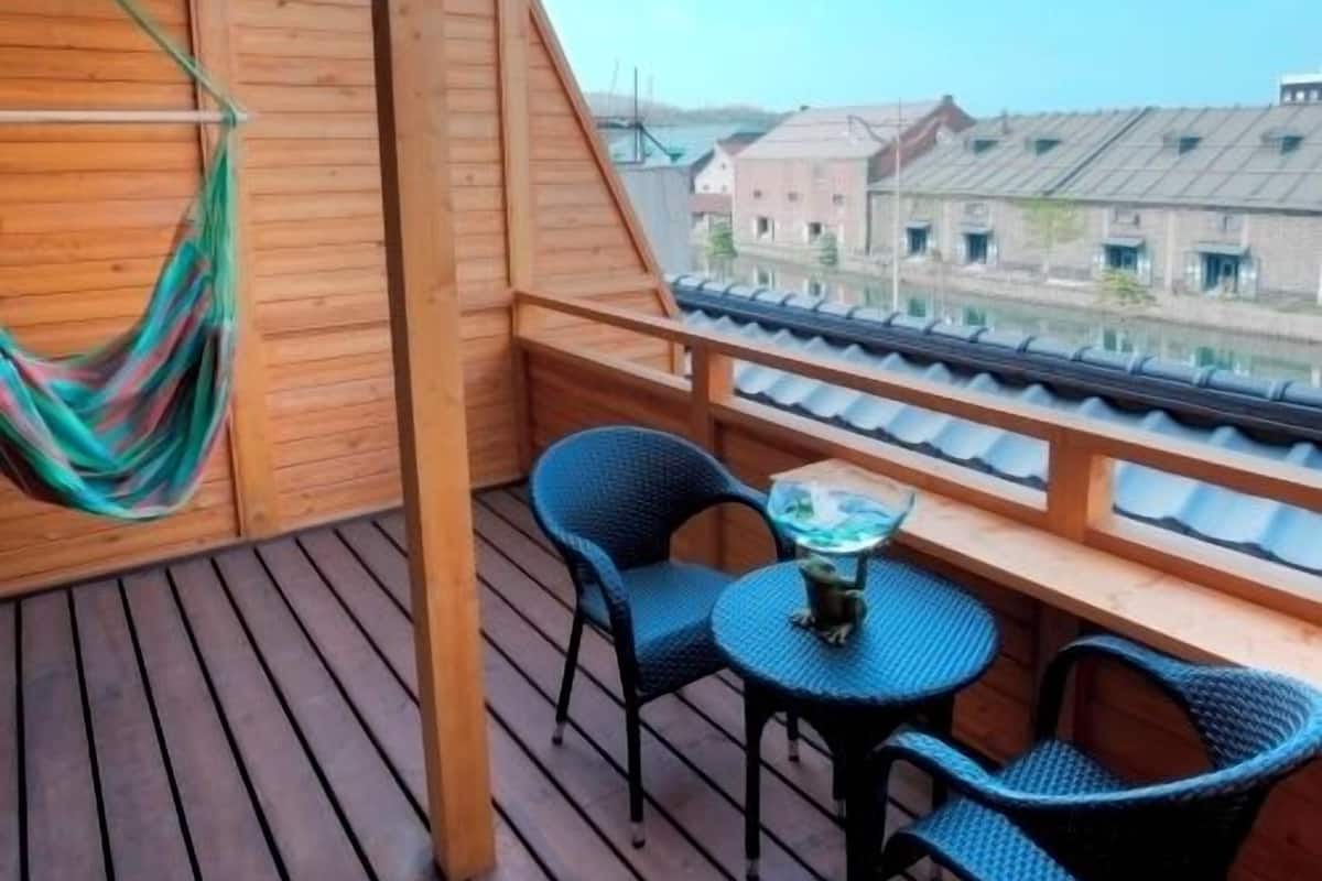 A wooden deck with a hammock, two chairs, and a small table.