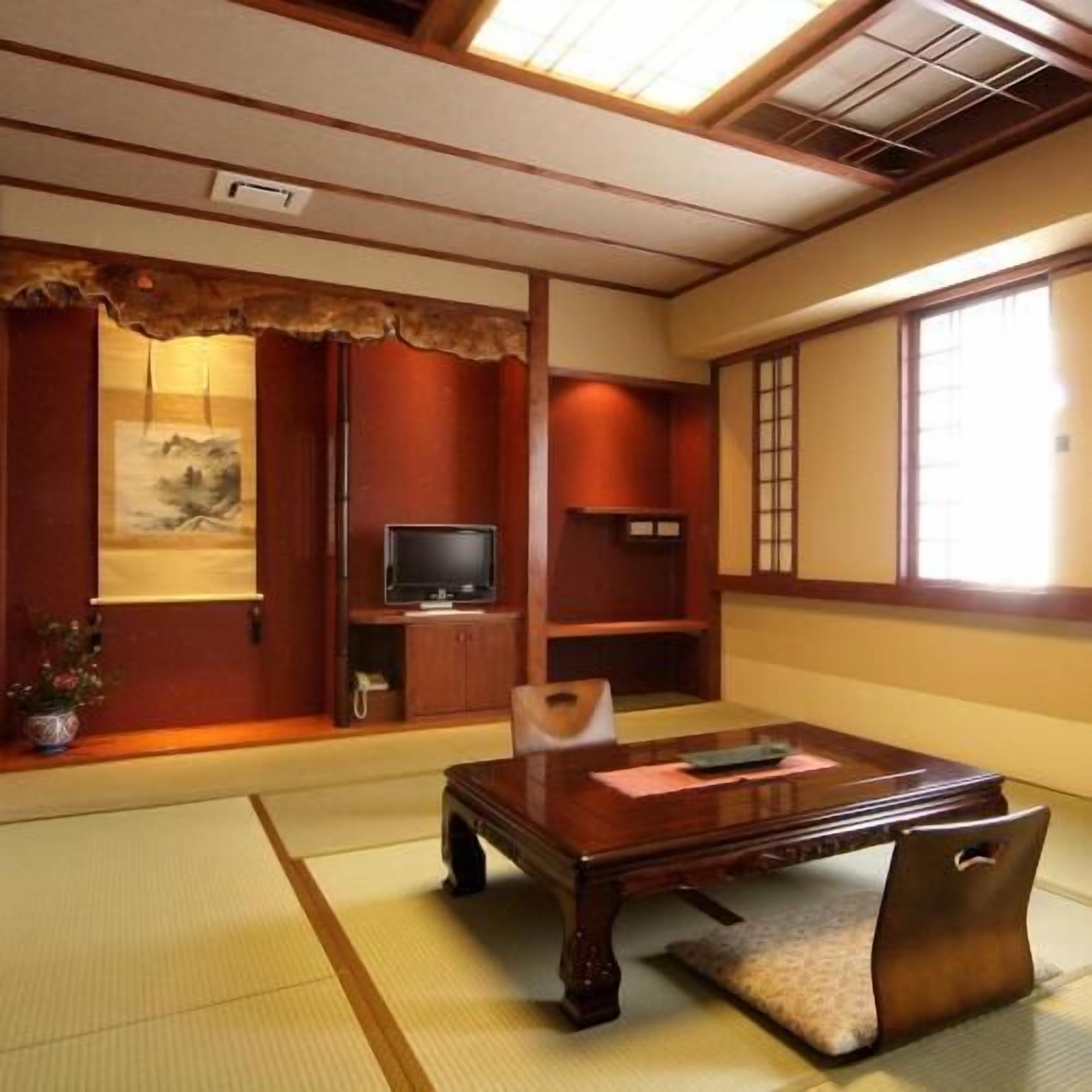 A traditional Japanese room with tatami flooring, a low wooden table, a television, and sliding doors.