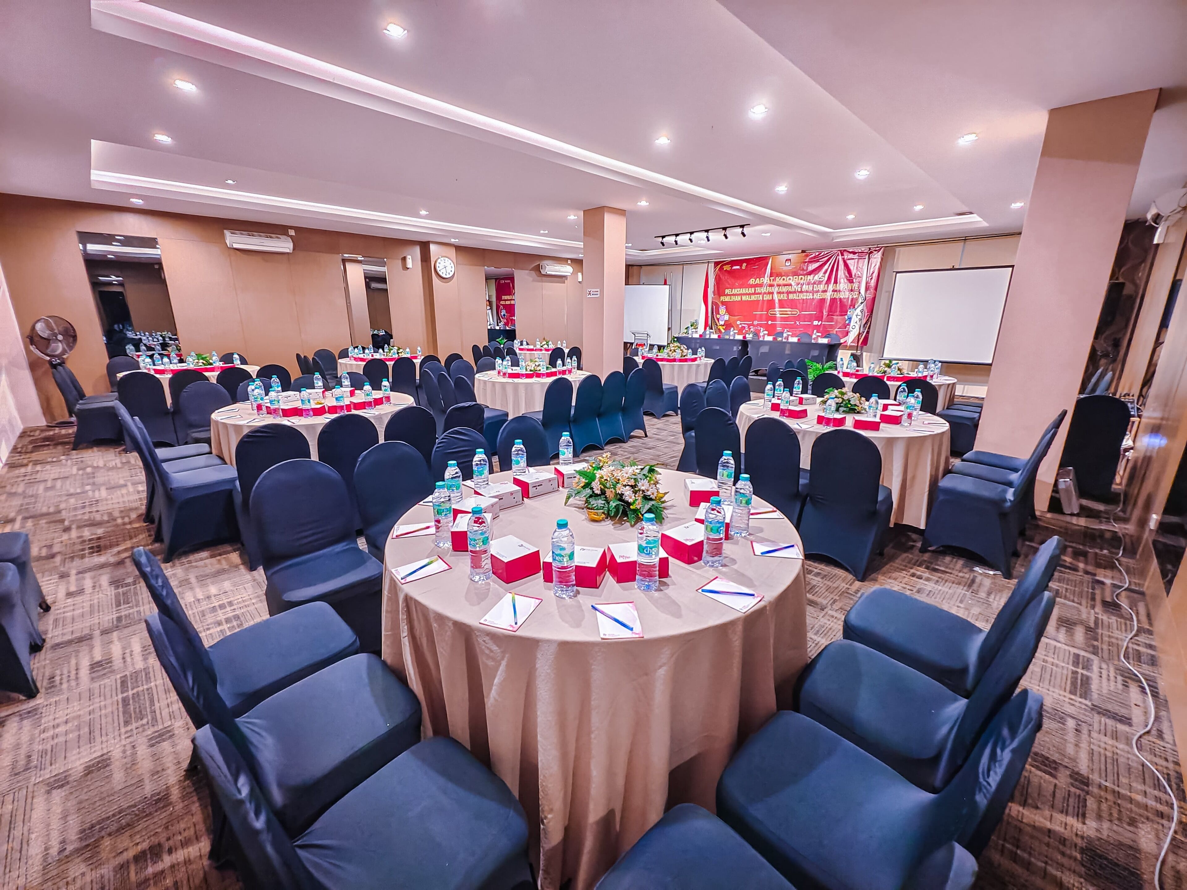 A conference room with round tables, chairs, and water bottles.
