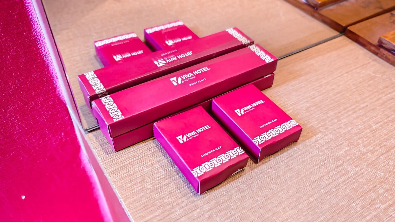 Un conjunto de cajas rojas con la etiqueta 'Viva Hotel' y la inscripción 'Gorrros de ducha' sobre un suelo de madera.
