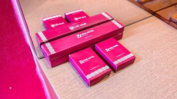 Un conjunto de cajas rojas con la etiqueta 'Viva Hotel' y la inscripción 'Gorrros de ducha' sobre un suelo de madera.