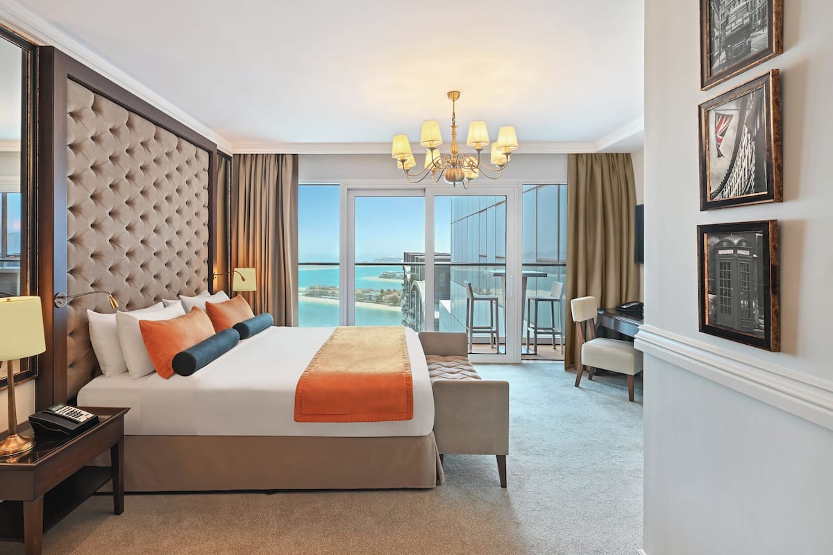 A hotel room with a large bed, a desk, and a view of the ocean.