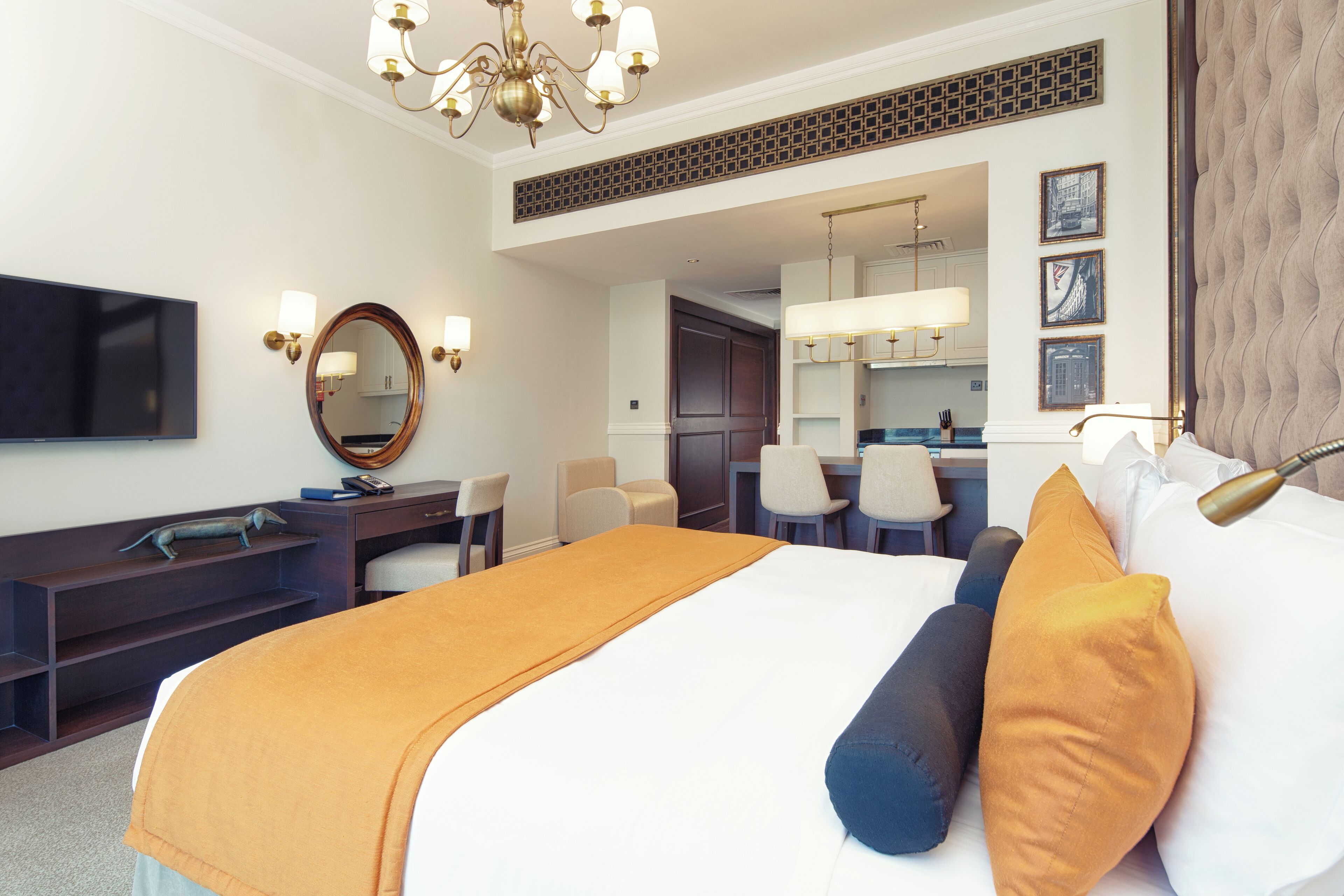 Une chambre d’hôtel avec un grand lit, un bureau, une télévision et, au fond, un coin repas.