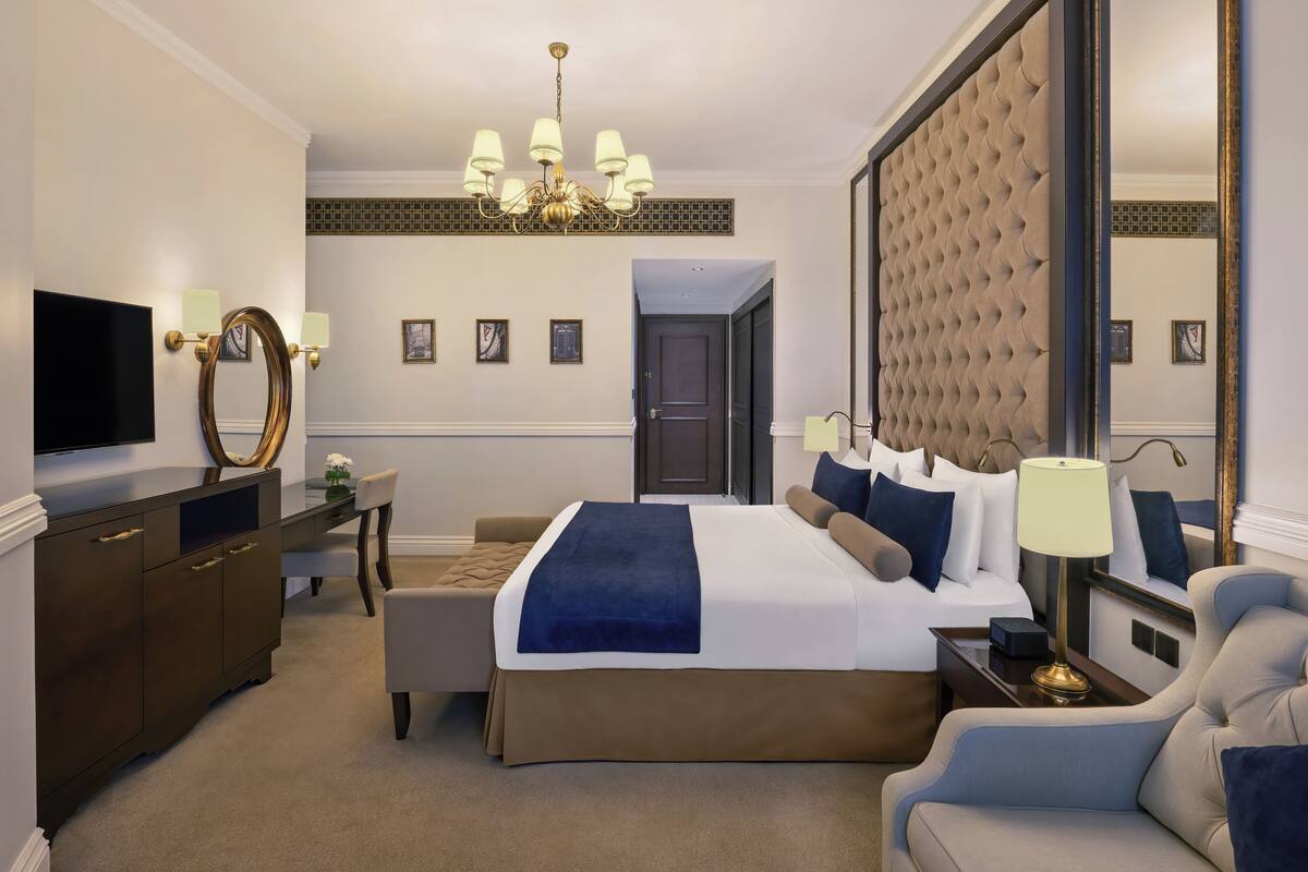 A hotel room with a large bed, a TV, a desk, and a chair.