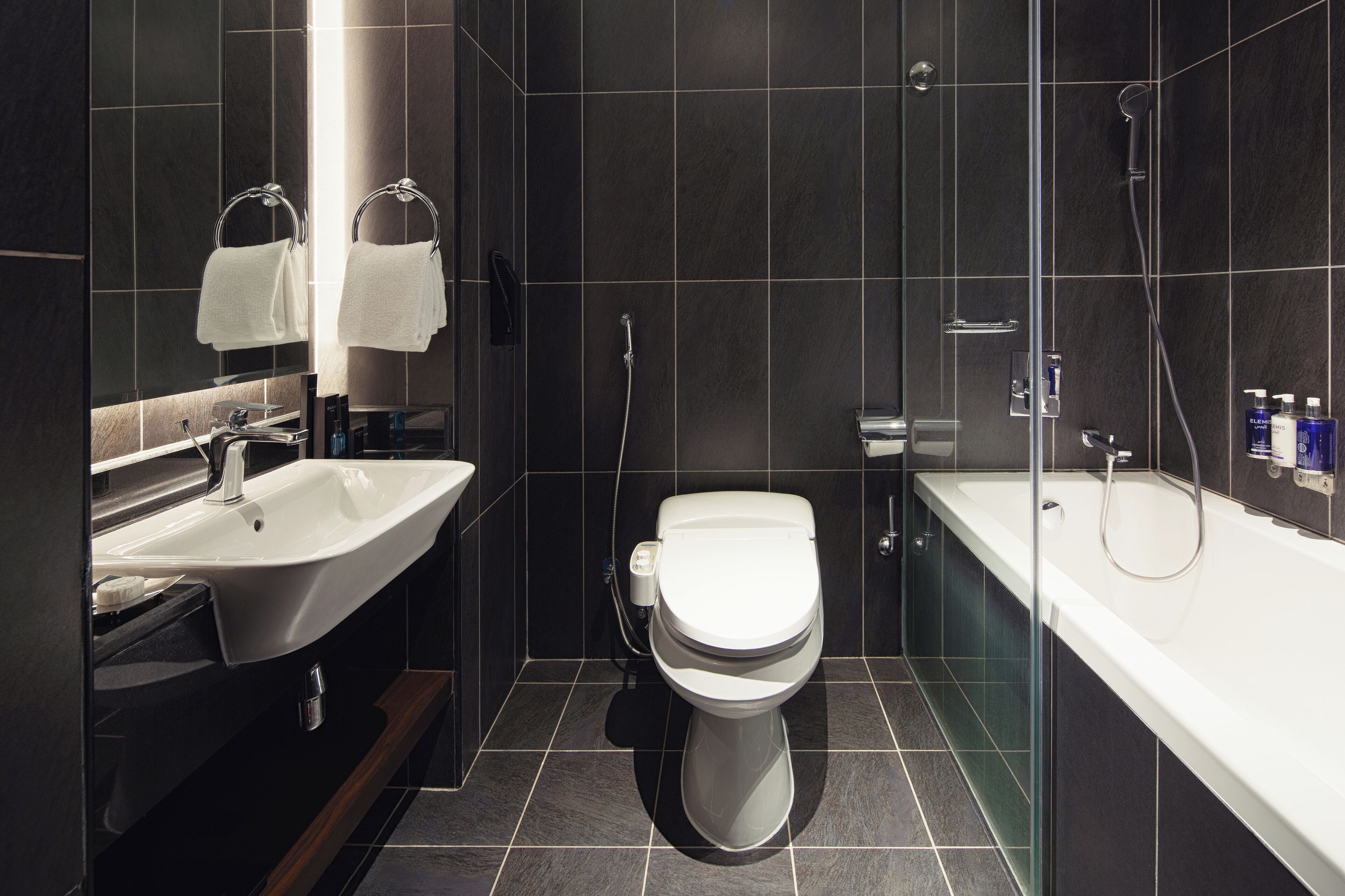 A modern bathroom with a white sink, toilet, and bathtub, all with chrome fixtures.