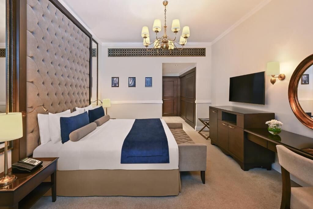 Ett hotellrum med en stor säng, en TV, ett skrivbord och en stol.