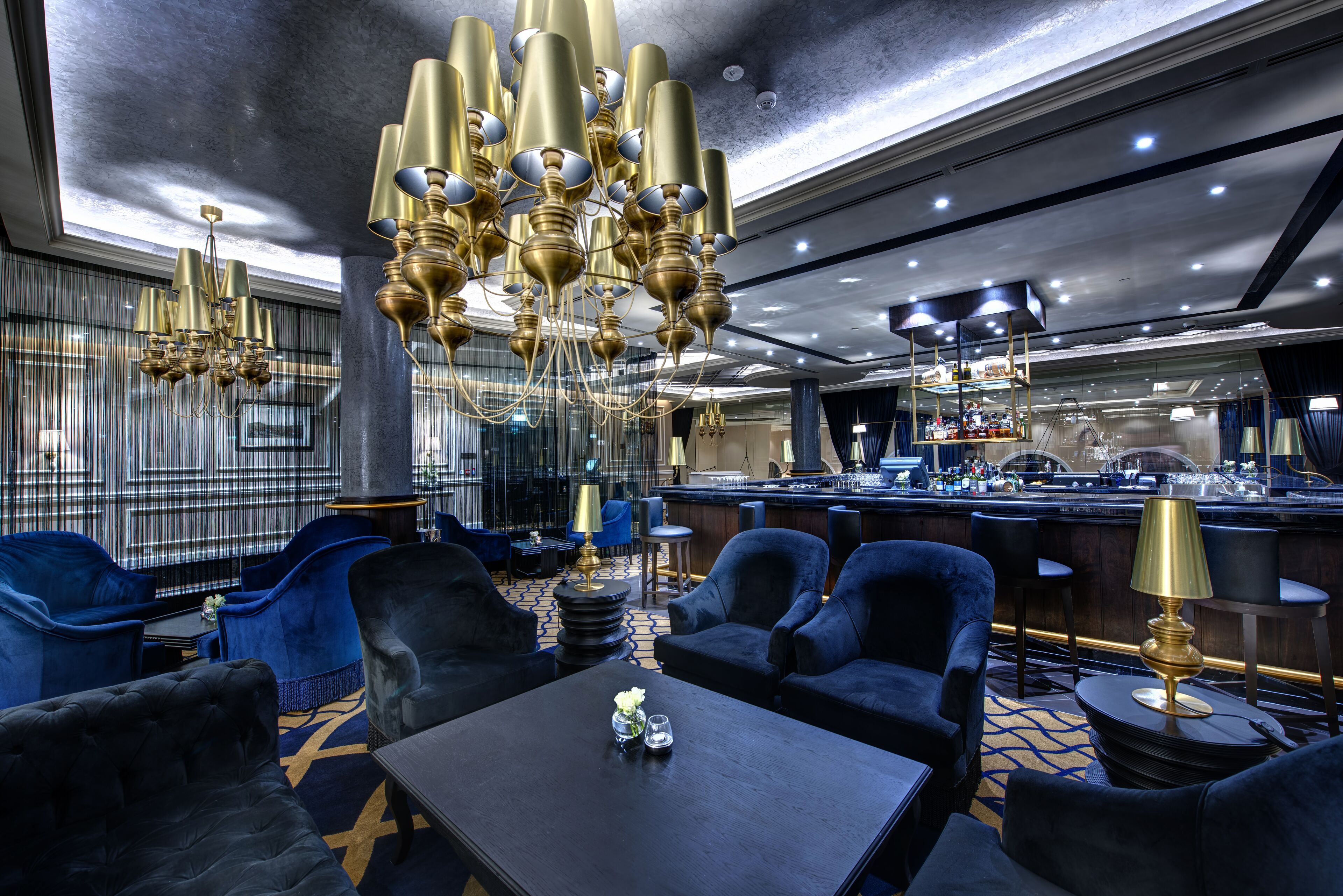 Eine luxuriöse Hotelhalle mit einem prächtigen Kronleuchter, komfortablen Sitzgelegenheiten und einer Bar.
