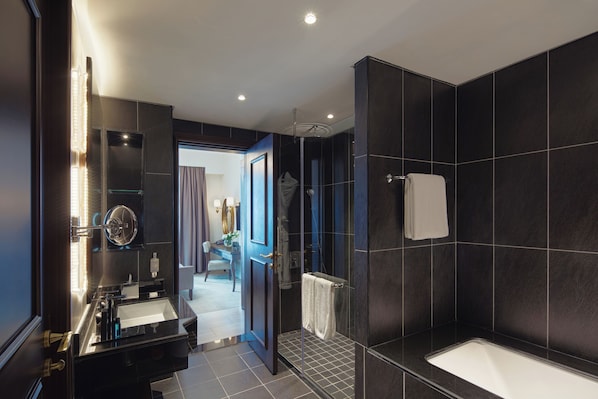 A modern bathroom with a large bathtub, a separate shower area, and a vanity with a mirror and lights.