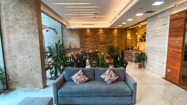 A modern lobby with a blue sofa, a round coffee table, and a stone wall.