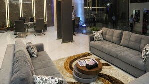 A modern living room with a large chandelier, grey sofas, and a coffee table.