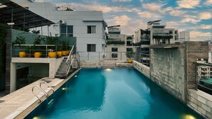 A rooftop swimming pool with a clear view of the sky and surrounding buildings.