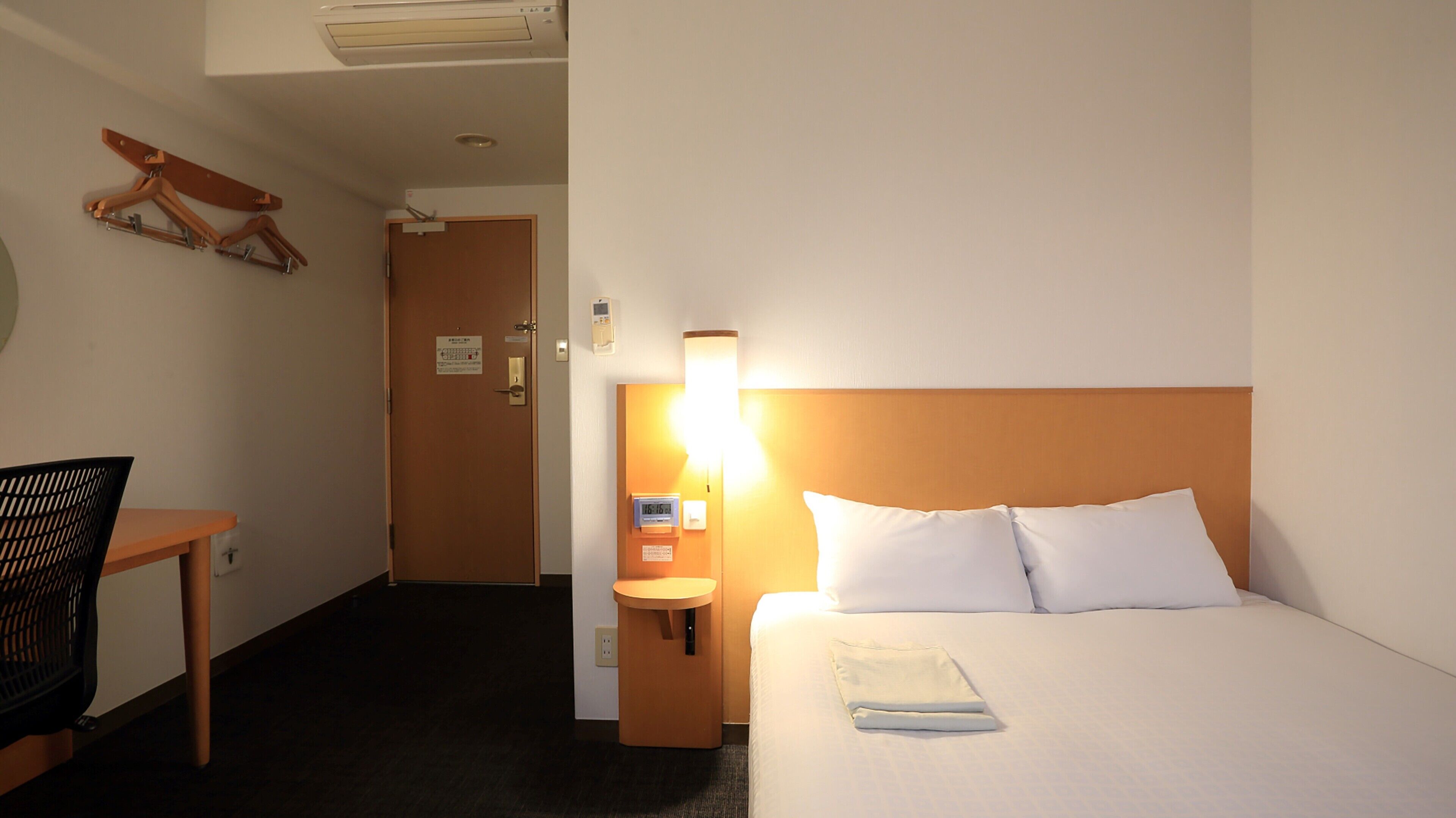 Une chambre d’hôtel avec un lit, une table de chevet, une lampe et une chaise.