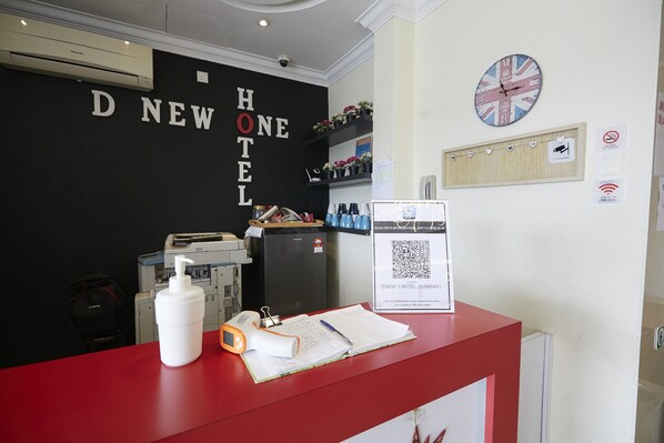 A hotel reception desk with a black wall displaying the name 'D NEW HOTEL'. There is a clock, a QR code, and a sign for room service. - D'New 1 Hotel Near Sunway Pyramid, 6 Min Only (Petaling Jaya)