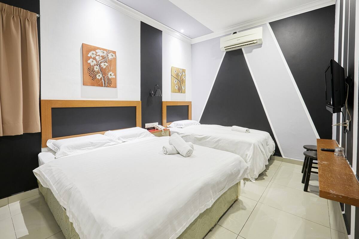 Une chambre d’hôtel avec deux lits, un bureau, une télévision et des œuvres d’art accrochées aux murs.