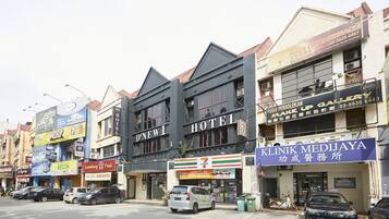 A hotel with a sign that reads "D'NEW1 HOTEL" and a 7-Eleven store across the street.