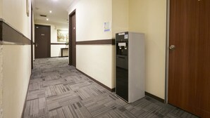 Een hotelgang met tapijtvloer, een waterdispenser en een deur met het nummer 202.