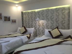 A hotel room with two beds, a patterned headboard, and a bedside lamp. - White Star Hotel (Xuan Huong - Da Lat)