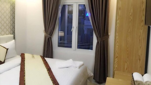 Una habitación de hotel con una cama, un armario de madera y una ventana con cortinas.