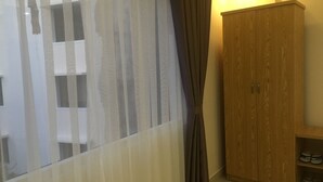 Una habitación con un armario de madera, un par de cortinas y un estante con zapatos.