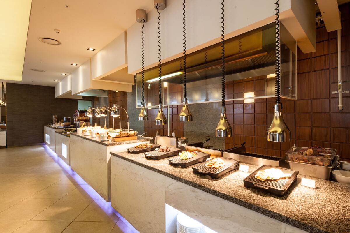 A modern kitchen with a marble countertop, multiple cooking stations, and pendant lighting.