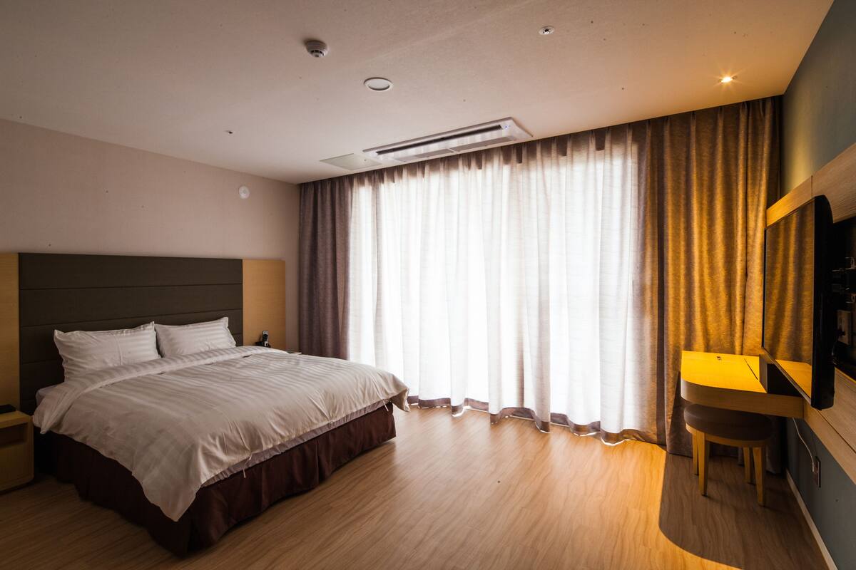 A modern hotel room with a large bed, a desk, and a television.