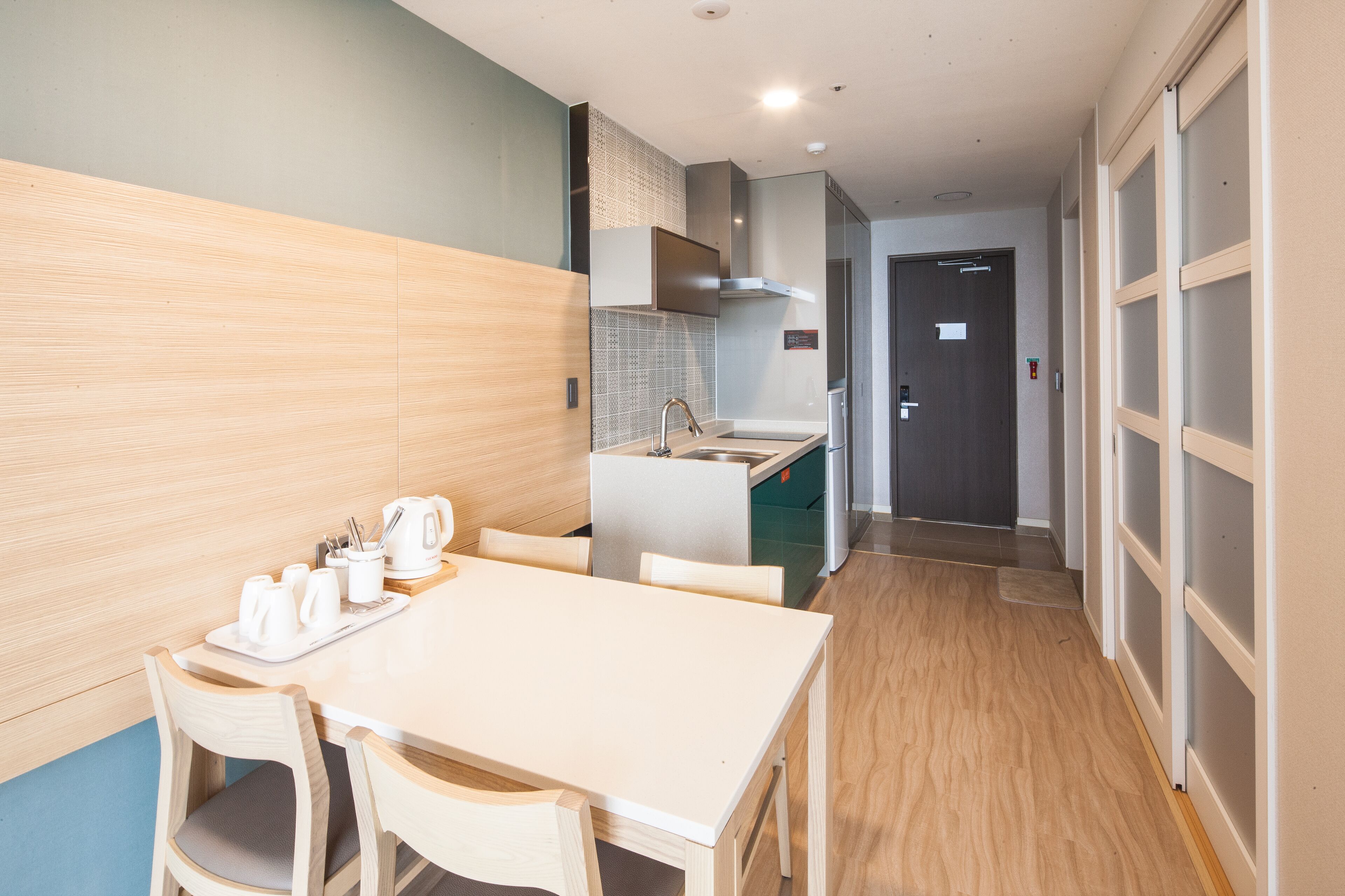 A modern kitchen with a dining area, featuring a white table, chairs, and a coffee station.