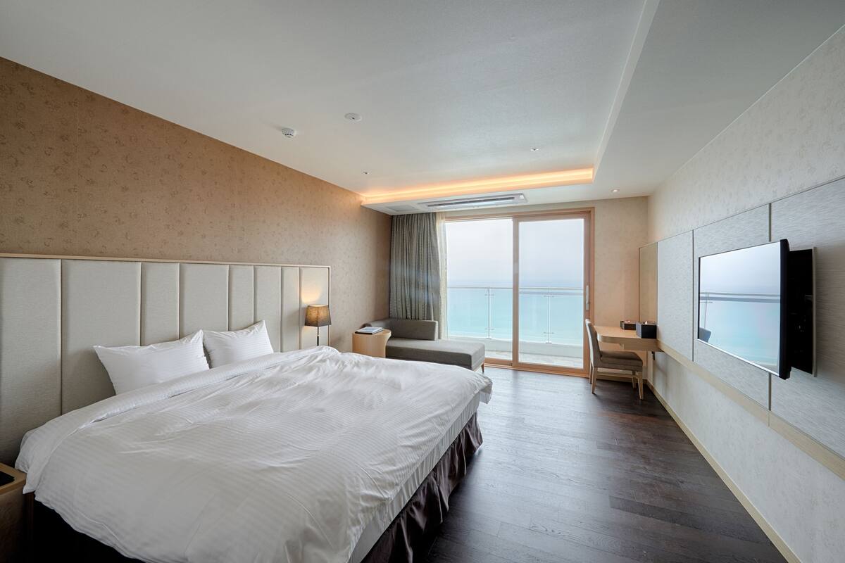 A hotel room with a large bed, a desk, and a TV.