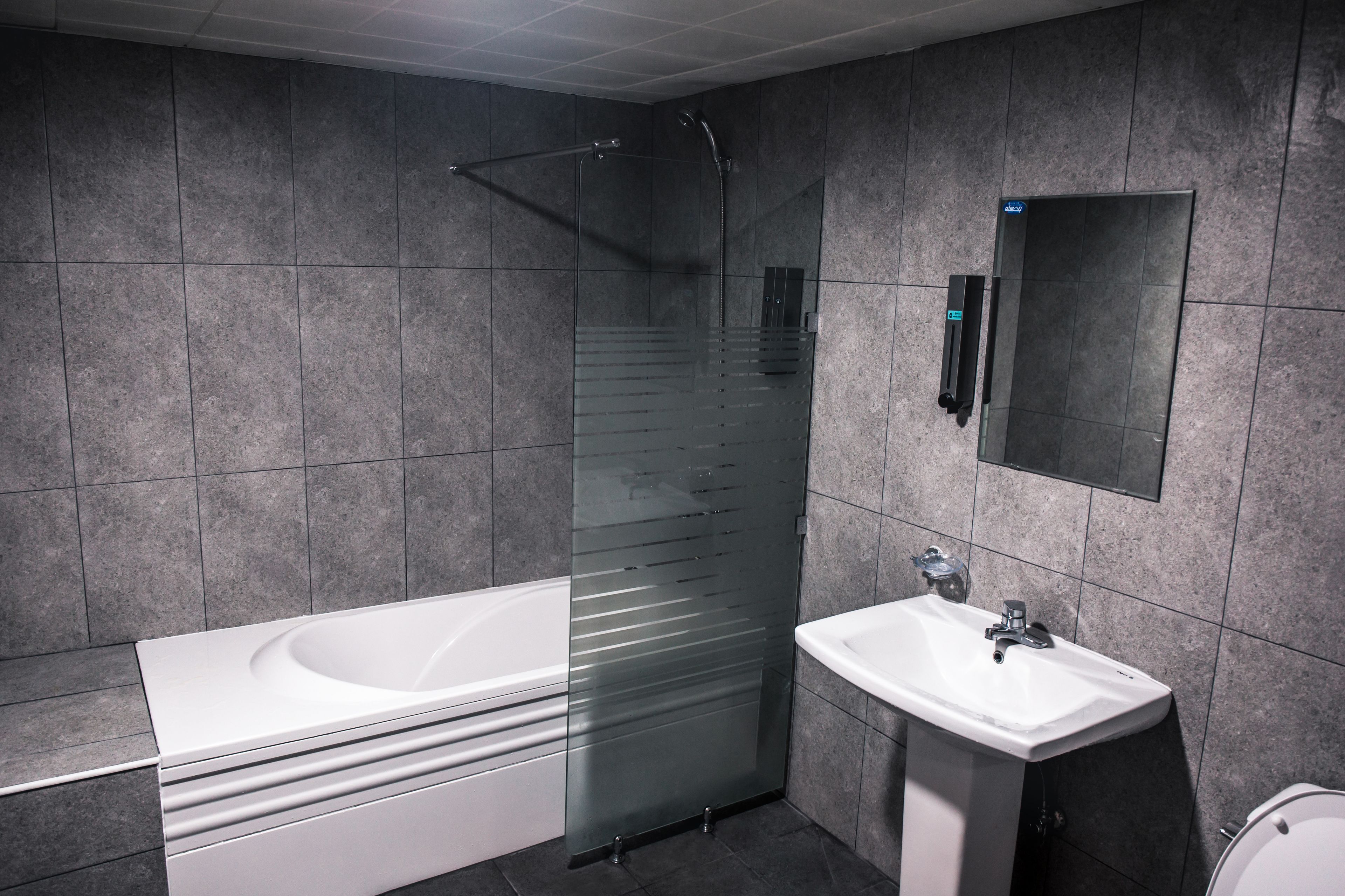 Ein modernes Badezimmer mit einer einbaubaren Duschkabine, einer weißen Badewanne und einem Waschbecken.